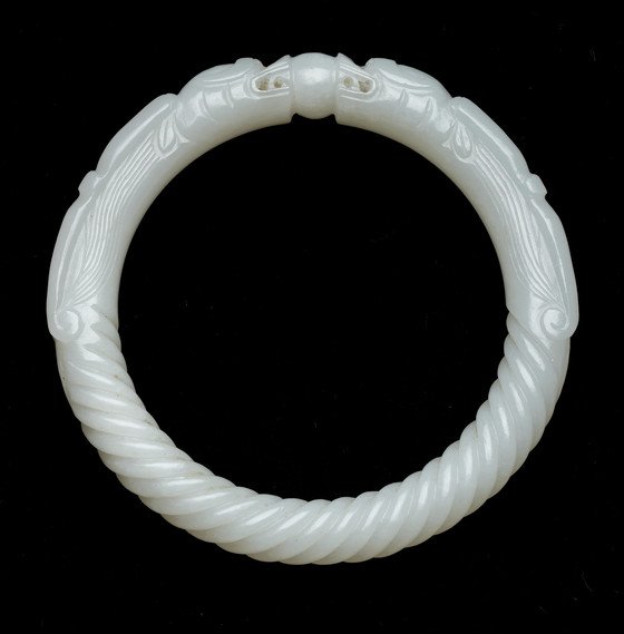 A bracelet featuring two dragon designs and a central pearl, crafted from a light-colored material.