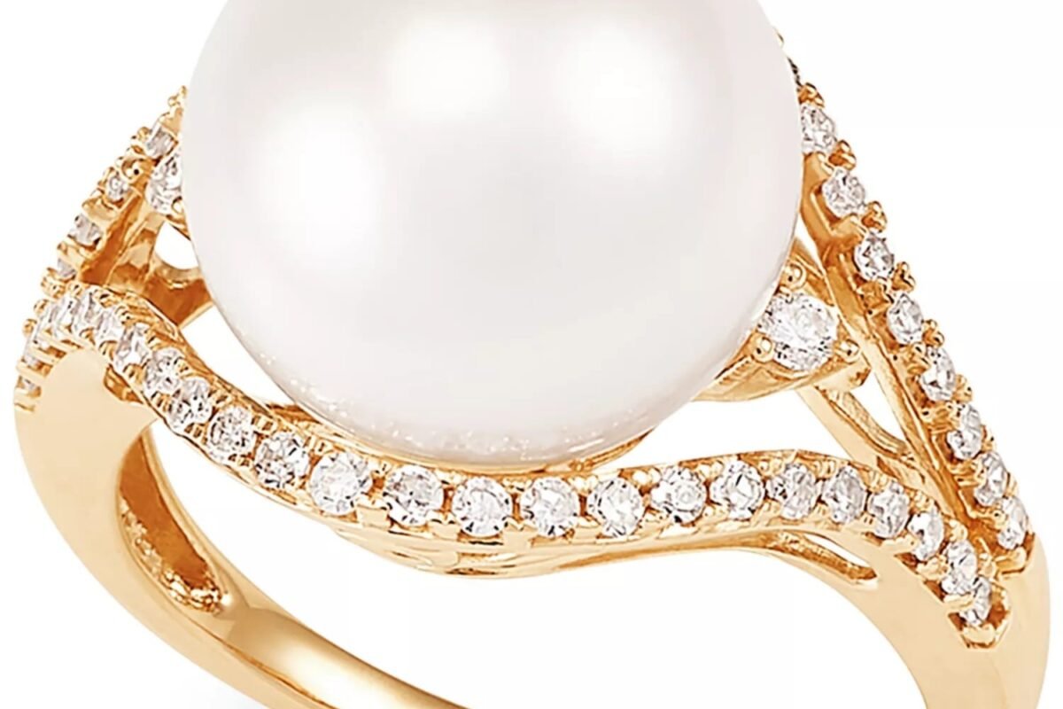 Gold ring featuring a large white pearl surrounded by small diamond accents on a decorative band.