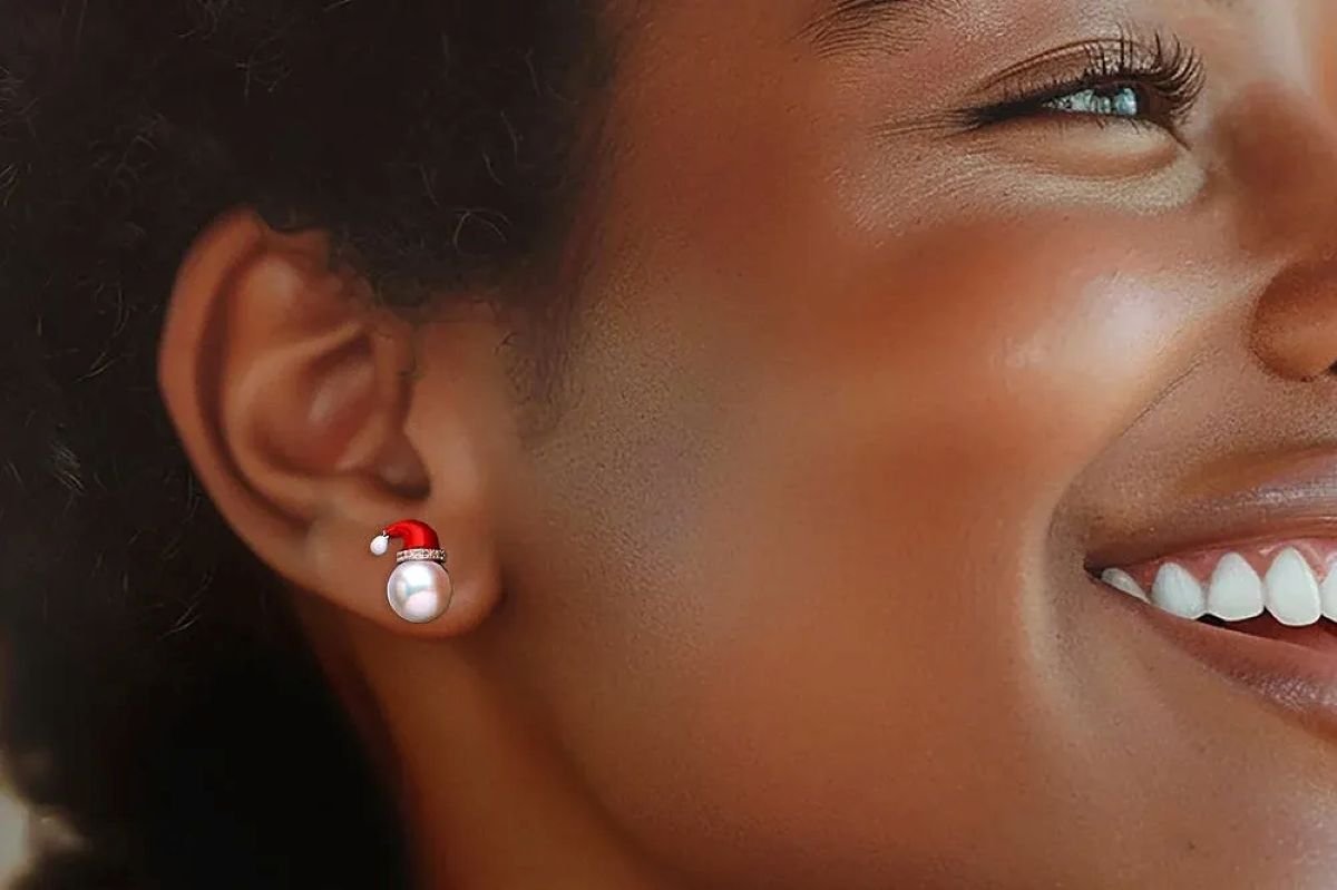 Close-up of a woman smiling, wearing pearl earrings with a red accent, showcasing a stylish accessory on her ear.