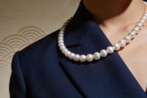 Sanae Takaichi-inspired white pearl necklace against a dark navy blazer, featuring a classic pearl strand that conveys timeless elegance and a strong, authoritative presence.