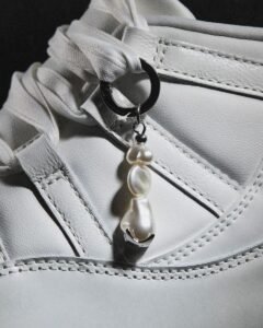 Pearl-inspired Air Jordan 11 keychain on a pearl-white sneaker lace, with a lustrous pearl charm and stitched detailing in soft silver tones.