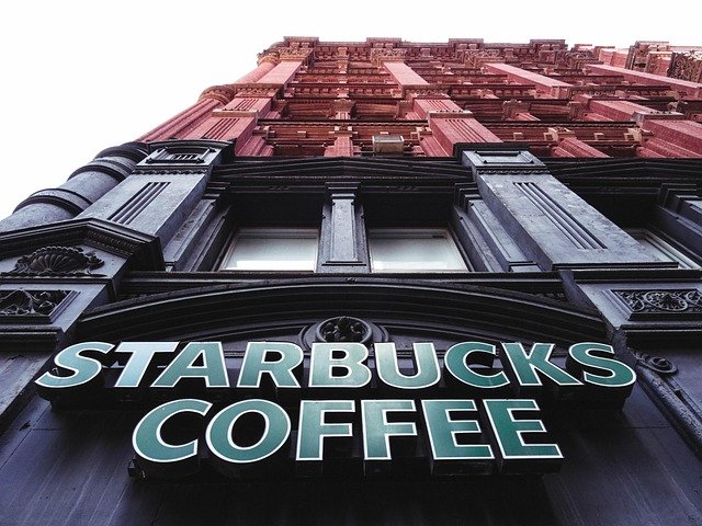 Bold teal Starbucks Coffee lettering on a dark facade with strong geometric lines, echoing the modern moment of pearls in branding.